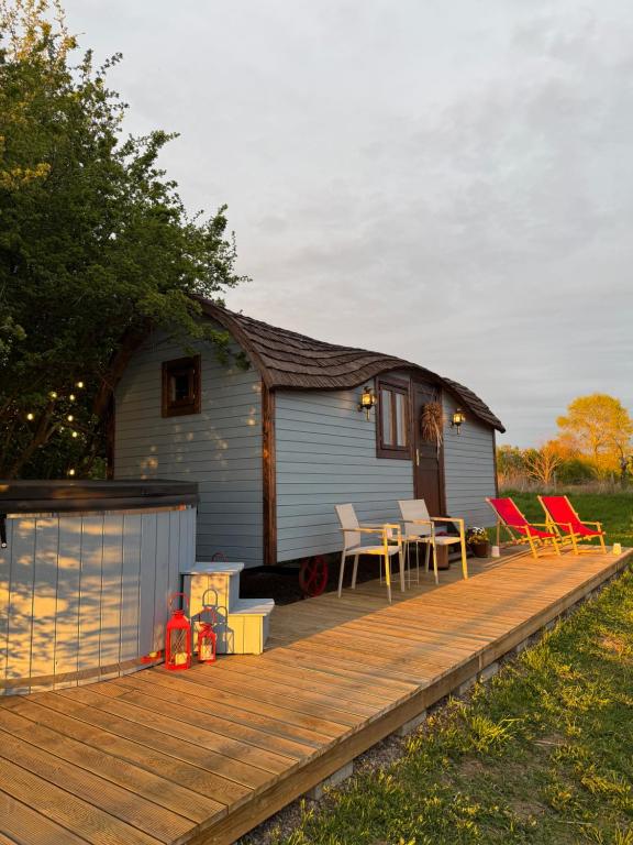 a house with a deck with chairs and a table at Żuławska Zielona Przystań, całoroczny domek na kołach Sikorka in Izbiska