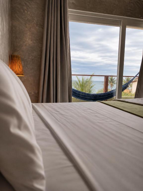 a bed with a window with a view of the ocean at Casas de Juan in Morro de São Paulo