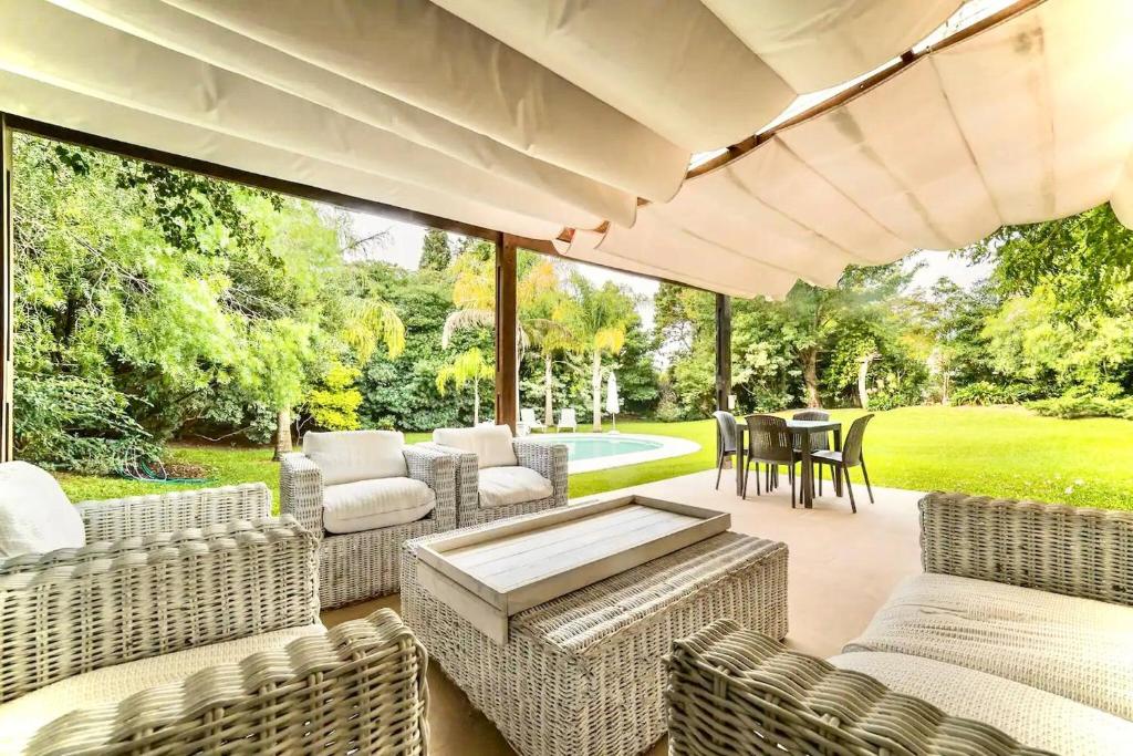an outdoor patio with wicker chairs and a table at Mansión en Beverly Hills in Punta del Este