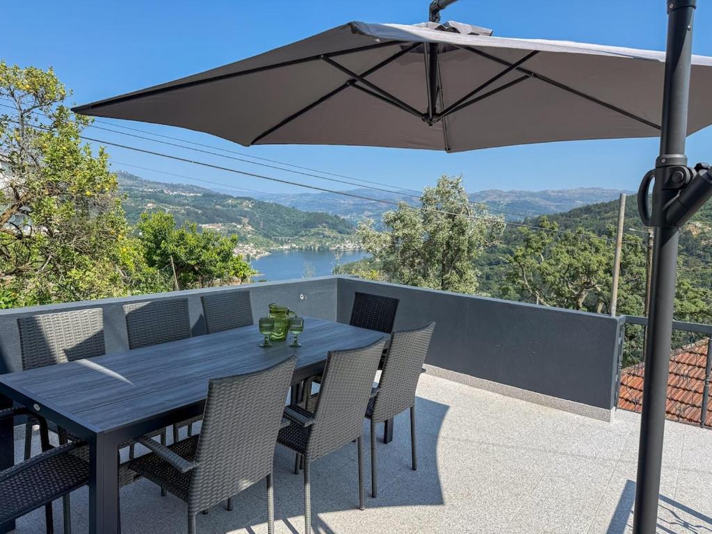 a table and chairs on a balcony with an umbrella at House overlooking the Douro-Casa das Almas in Paços de Gaiolo