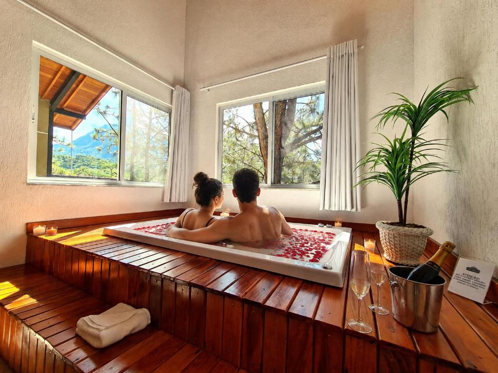 two people sitting in a bath tub in a room at Pousada Serra da Índia in Penedo