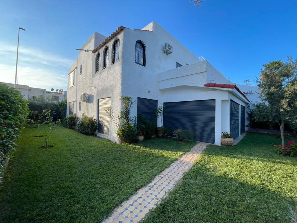 una casa bianca con garage e giardino erboso di Basatine a Saïdia