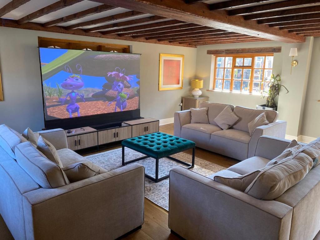 a living room with two couches and a flat screen tv at 8 BR Luxury Farmhouse | Tennis Court & EV Charging in Tile Hill