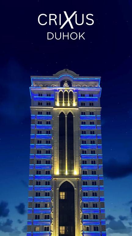 a tall building with lights on it at night at Crixus Hotels Duhok in Duhok