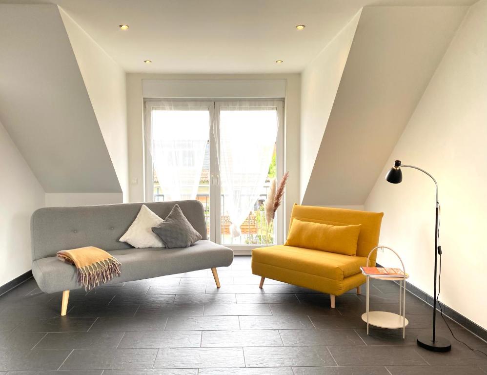 a living room with a couch and a yellow chair at Midi-Maisonette mit kleiner Dachterrasse und Blick ins Grüne in Petersberg