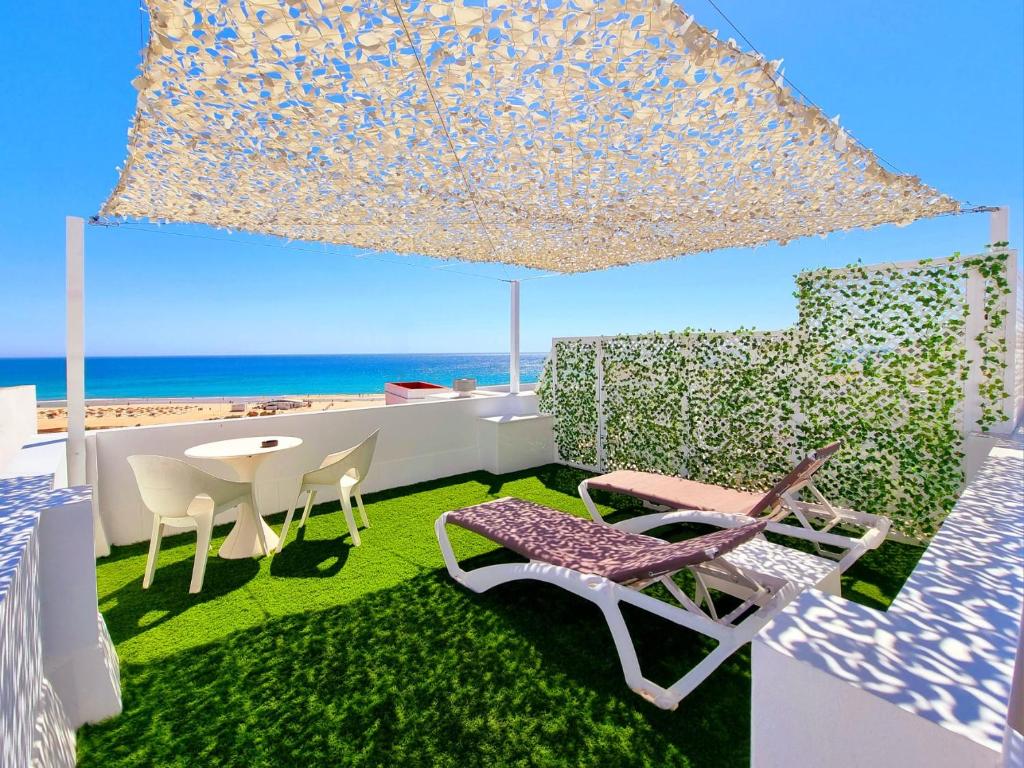 a room with a table and chairs and the beach at Apartamentos El Arrecife in Conil de la Frontera