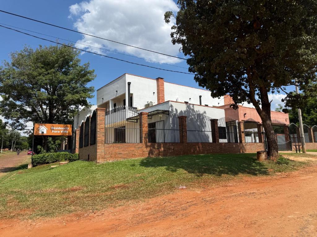 a building on a dirt road next to a tree at Residencia Pura Vida in Capiatá