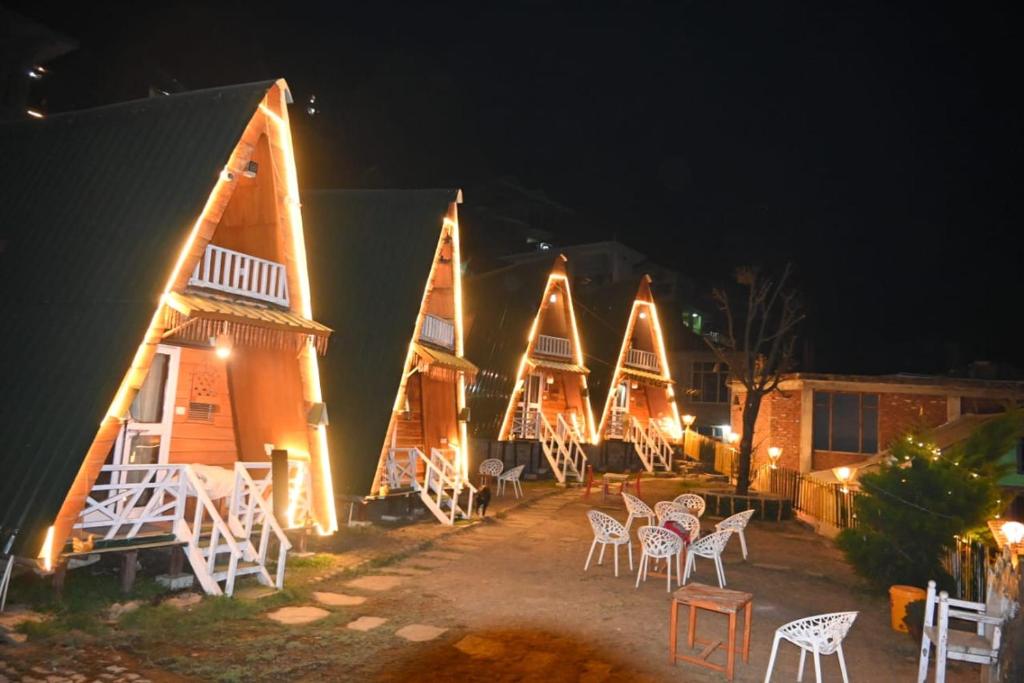 a group of buildings with white chairs and lights at Chilux Manali in Manāli