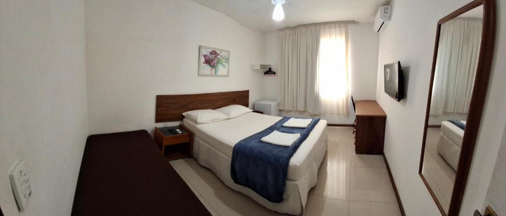 a small hotel room with a bed and a window at Solar da Praia in Vitória