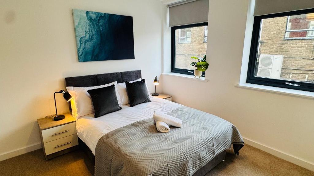 a bedroom with a bed and two windows at Central Old Town 1-Bed Apartment in Swindon