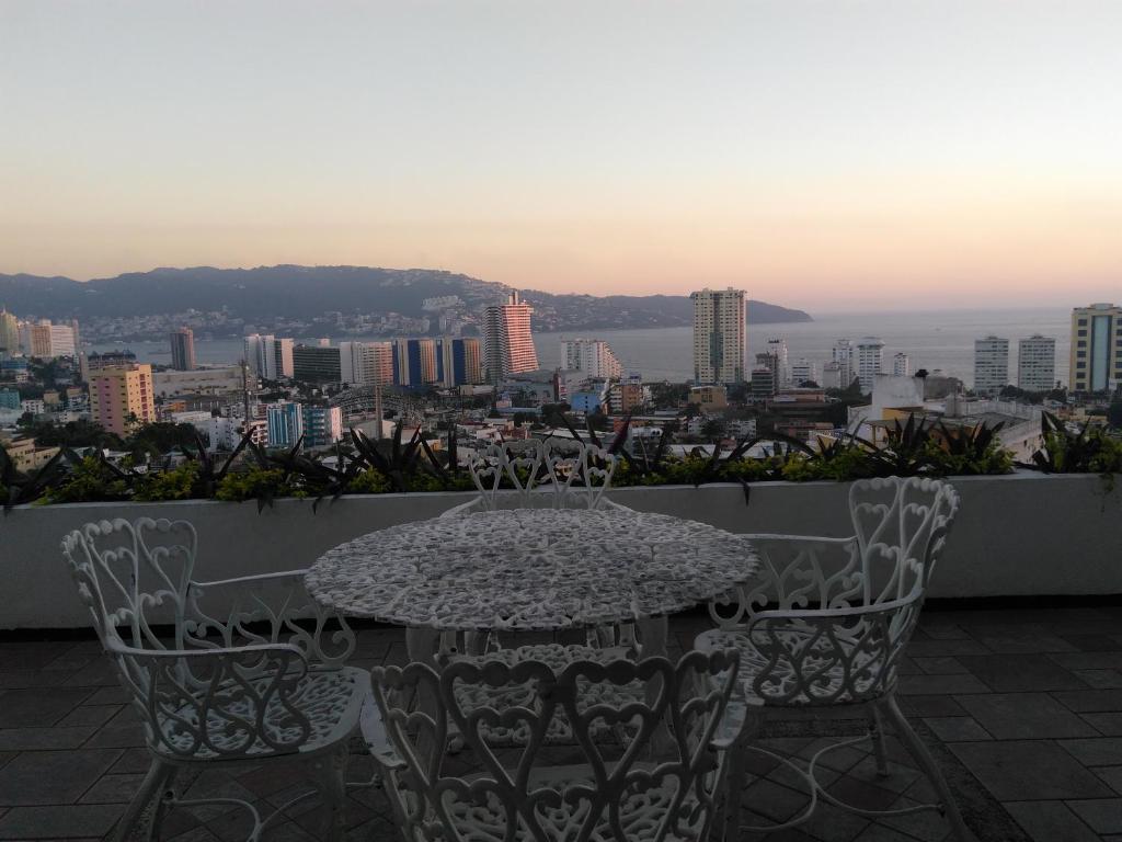 a table and chairs on a balcony with a view of a city at Casa Horizonte Azul Acapulco in Acapulco