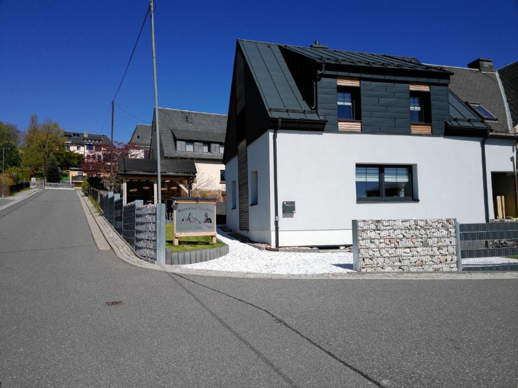 a white house with a black roof on a street at Ferienhaus Anton Günther in Bernsbach