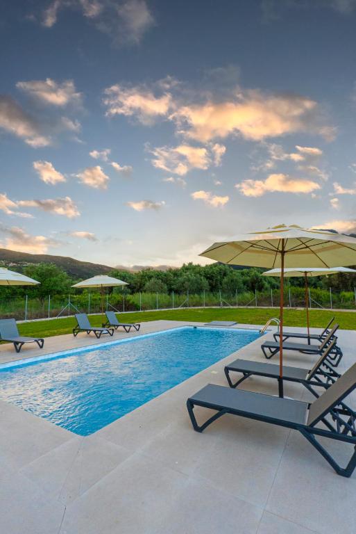 a pool with two lounge chairs and an umbrella at Villa Demetrious in Kondáraina