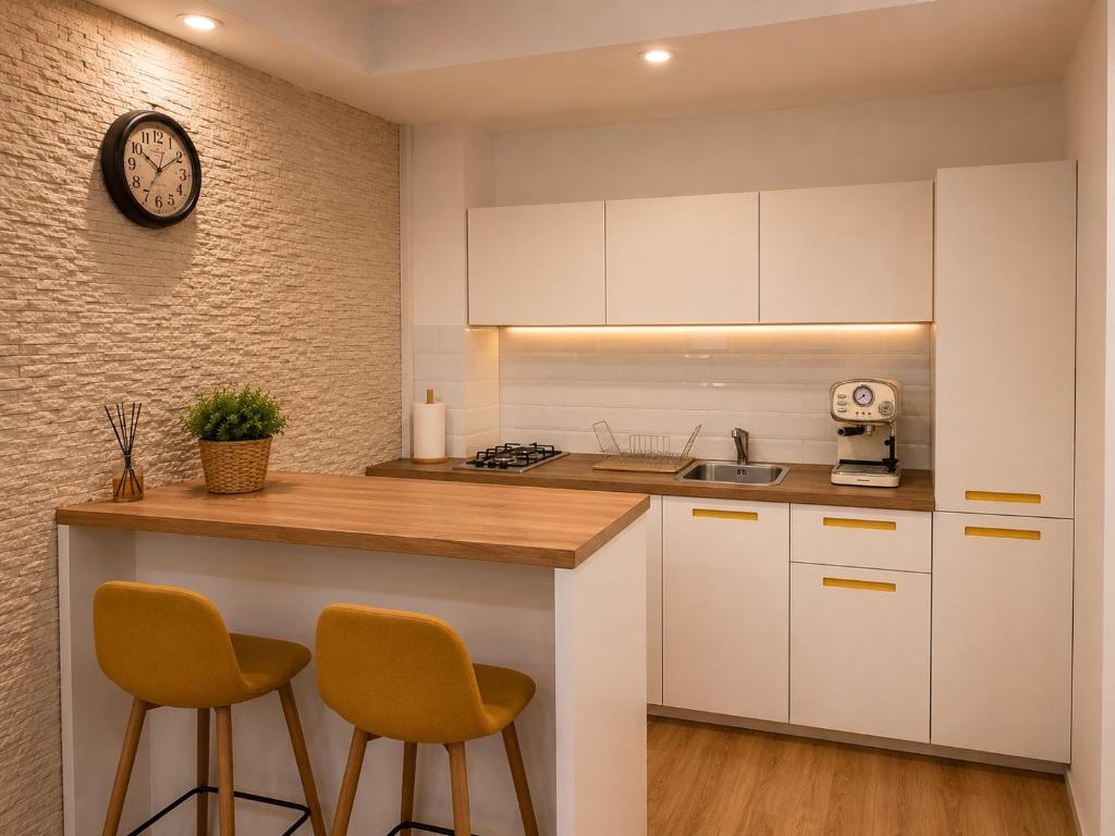 a kitchen with white cabinets and a counter with two chairs at Liberty Deluxe Apartment Cosmopolis in Creţuleasca