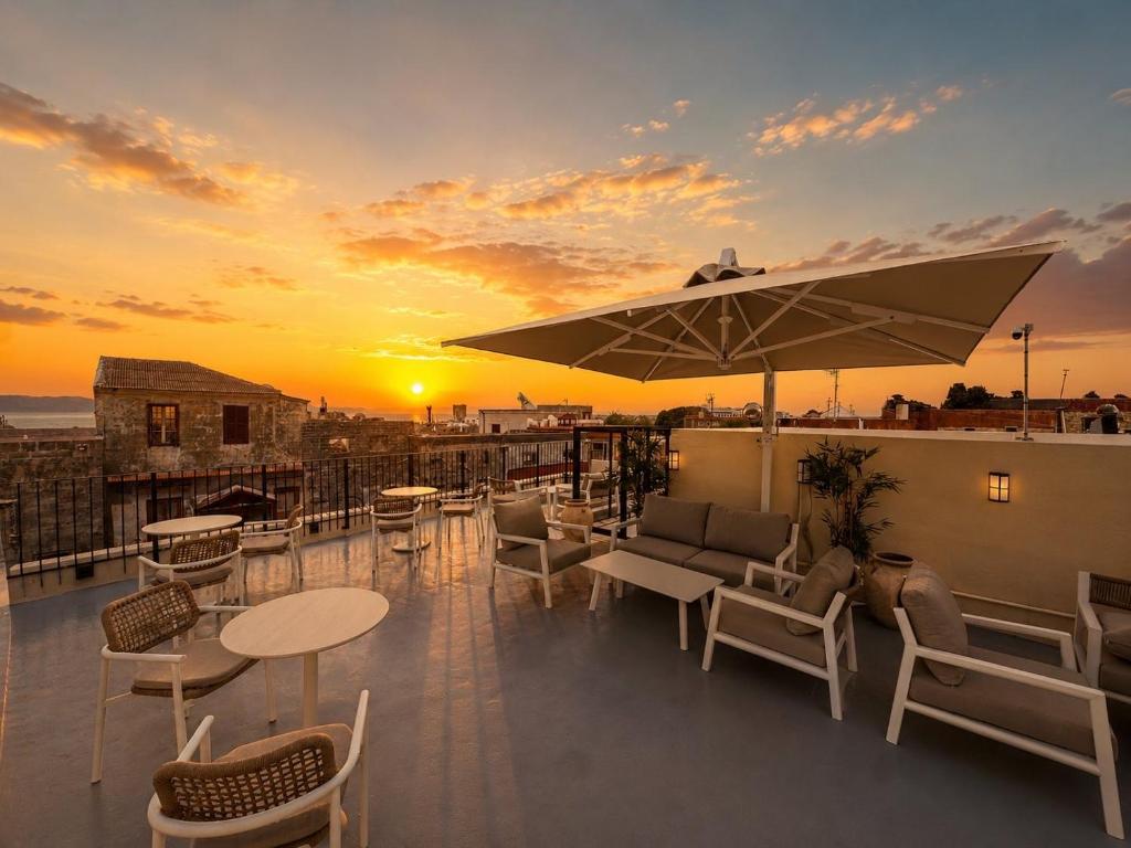 a rooftop patio with tables and chairs and a sunset at Karavel Suites - Old Town Boutique Rooms in Rhodes Town