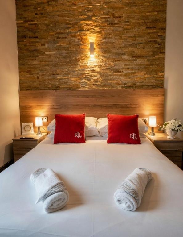 a bedroom with a large white bed with red pillows at The Bromley's in Great Yarmouth