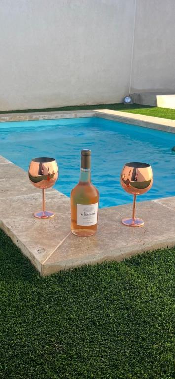 a bottle of wine and two chairs next to a swimming pool at Studio Provence in Istres