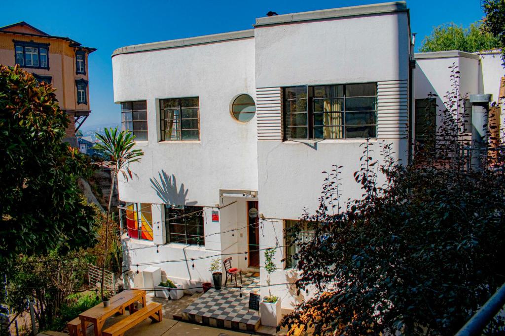 a white house with a bench in front of it at Hostel Hotzenplotz Alegre in Valparaíso