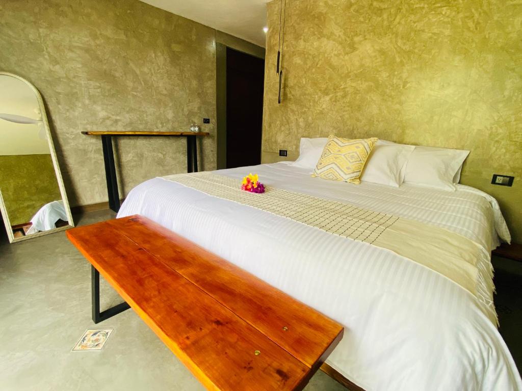ein Schlafzimmer mit einem großen Bett und einer Holzbank in der Unterkunft Hotel Casa Grangelo in Atlixco