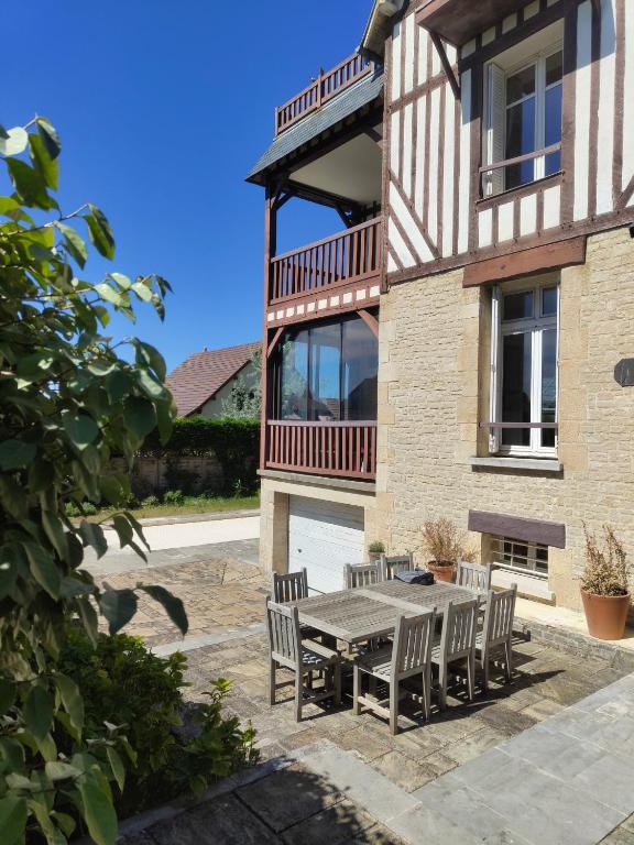 a patio with a table and chairs in front of a house at la villa avezard in Blonville-sur-Mer
