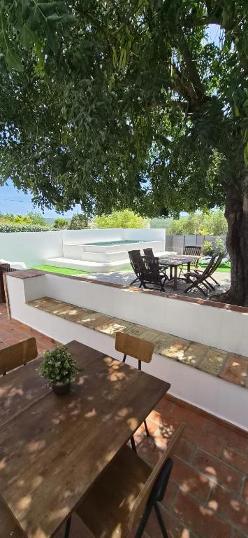 a patio with a wooden table and chairs under a tree at Cosy Country House in Cerro da Cova