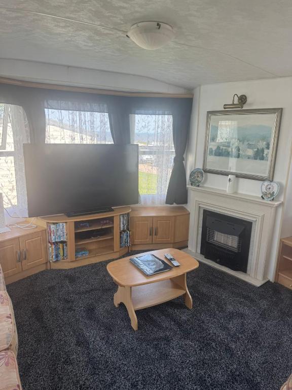 a living room with a flat screen tv and a coffee table at Kathy's Warden springs caravan in Leysdown-on-Sea