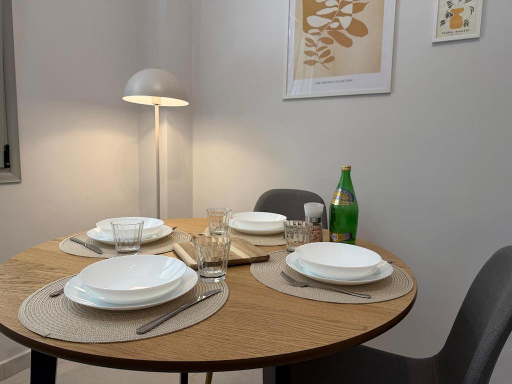 a wooden table with plates and glasses and a bottle at Lavandula in Xanthi