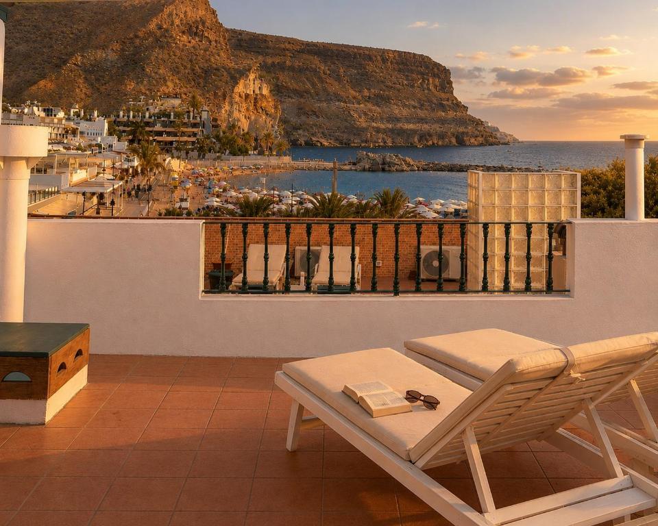 a balcony with a chair and a view of the ocean at Deluxe Mogán Beach Apt 2 in Puerto de Mogán