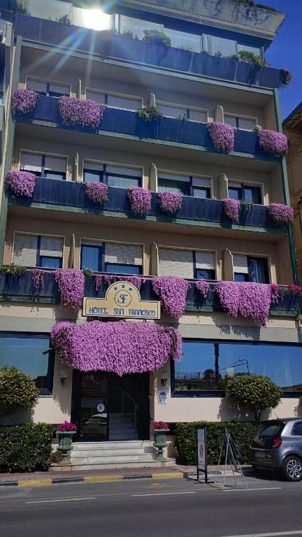 a building with purple flowers on the balconies at Hotel San Francisco in Viareggio