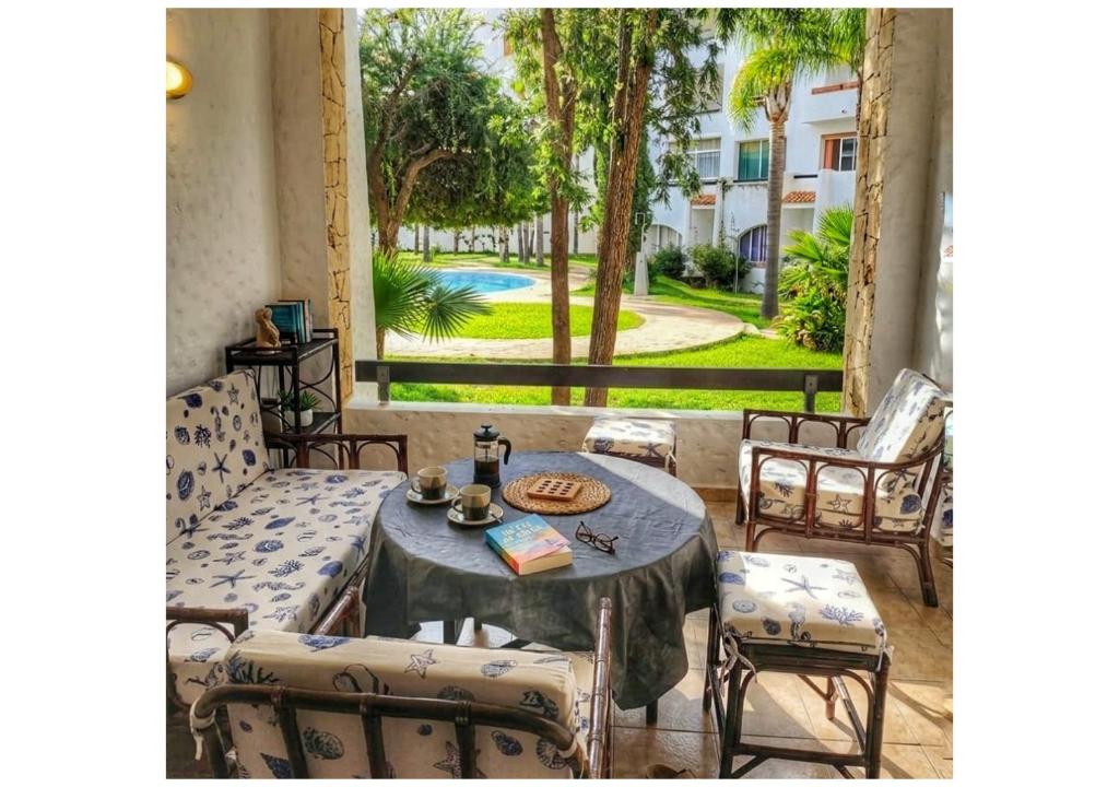 a patio with a table and chairs and a view at L'Olivier à Marina Golf Vue sur Piscine, Wi-Fi et Clim in Asilah