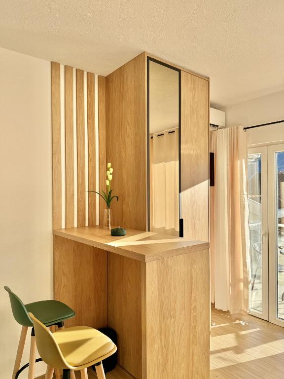 a kitchen with wooden cabinets and a green chair at Modern Beachfront Apartment in Đenovići
