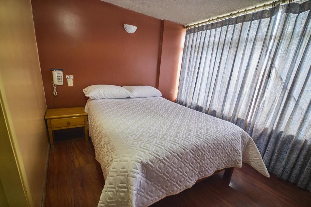 ein kleines Schlafzimmer mit einem Bett und einem Fenster in der Unterkunft Hotel Los Alamos in Riobamba