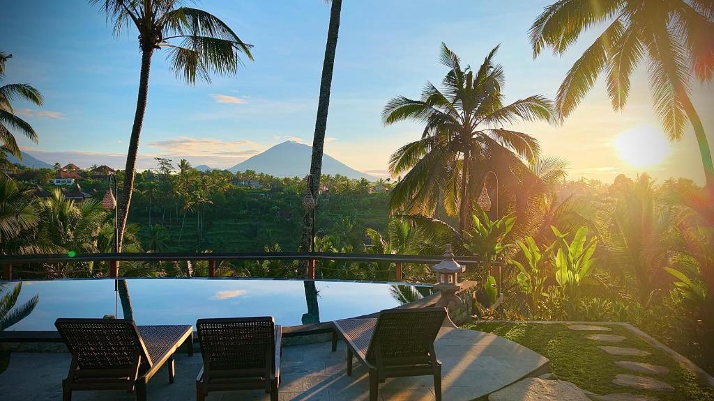 a pool with chairs and a view of a mountain at Puri Diamond Villas in Tampaksiring