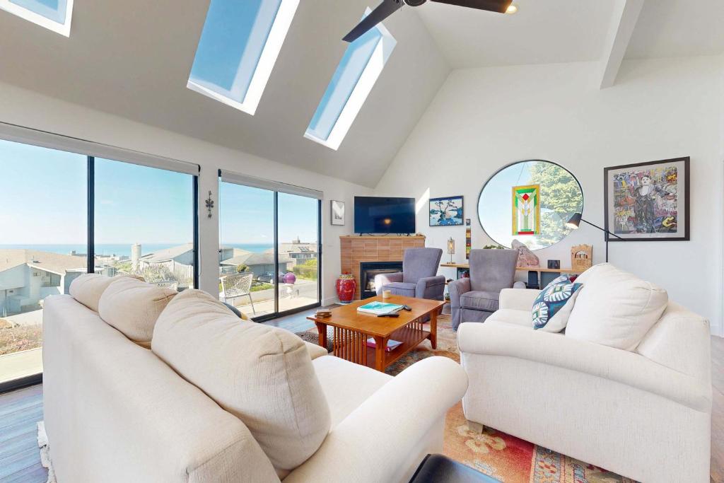 a living room with white furniture and large windows at Heron Escape in Bodega Bay