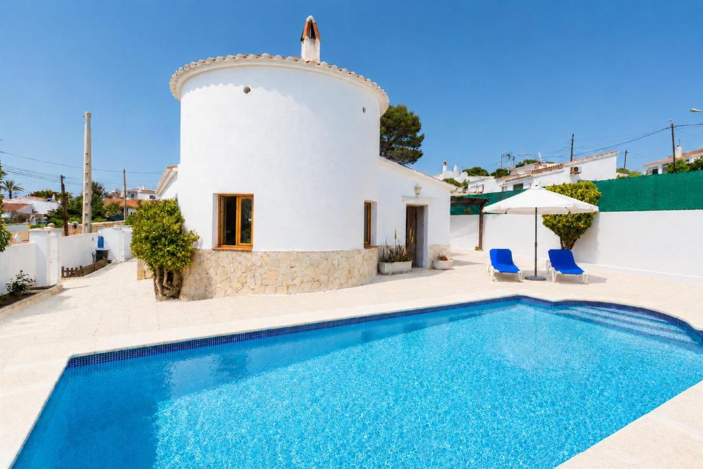 a villa with a swimming pool in front of a building at Villa Maria Large Private Pool AC WiFi in Cala en Porter