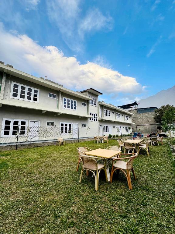a group of tables in the grass in front of a building at The Yak Motel in Skardu