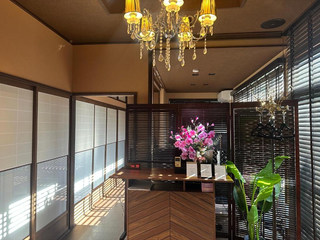 a dining room with a table with flowers and a chandelier at Guest House "Ro"kumano in Shimonoseki
