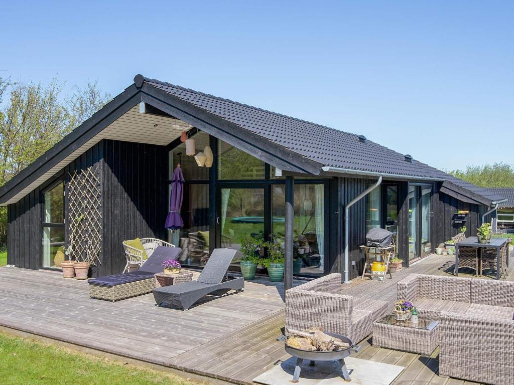 a black house with a deck with chairs and tables at Seaside Stay with the Sauna in Hørve