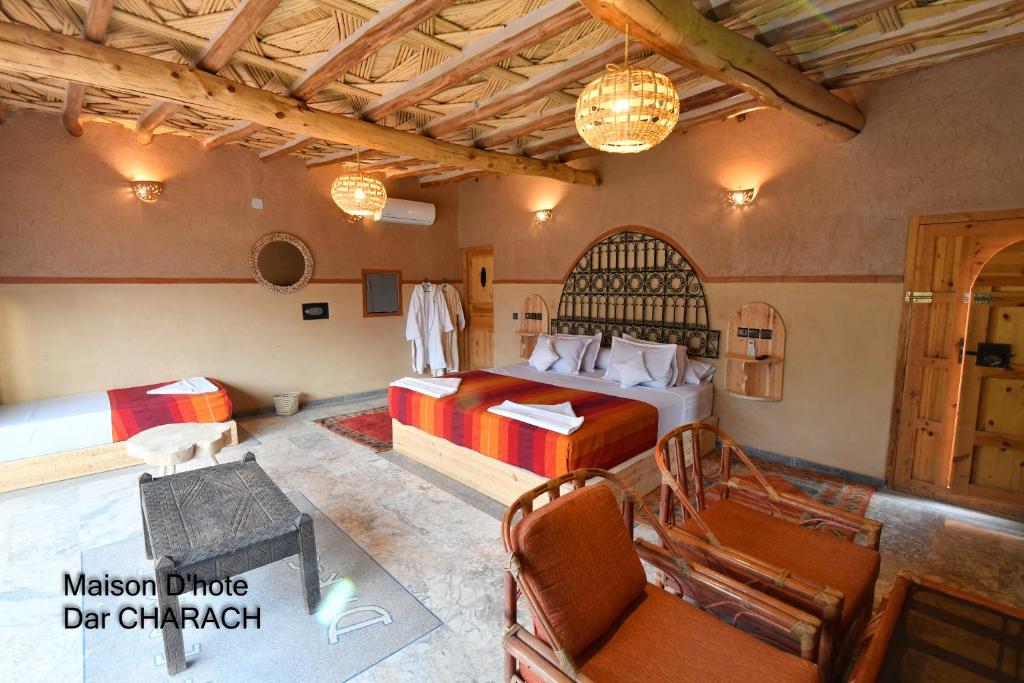 a bedroom with a bed and a table and chairs at Maison d hôtes Dar Charach in Ouarzazate