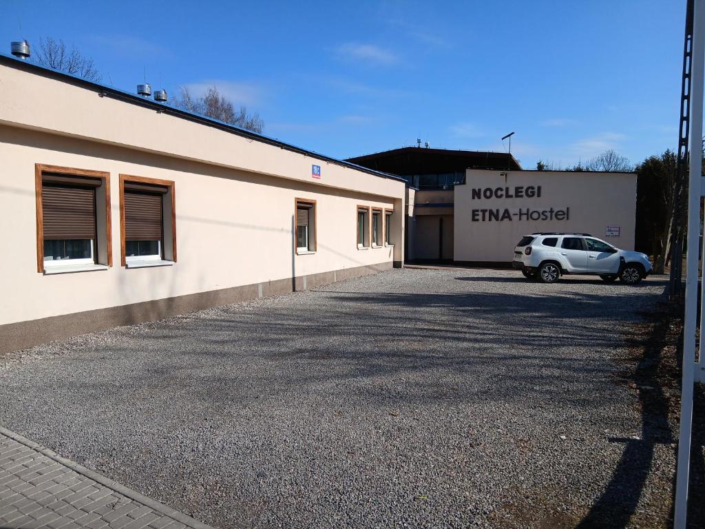 a building with a car parked in a parking lot at ETNA - Hostel -Noclegi Rzeszów 24 Pokoje -PARKING- in Rzeszów