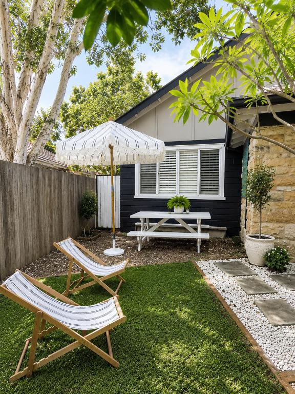 a patio with two chairs and an umbrella and a picnic table at Avalon Beach Cottage- The Islander in Avalon