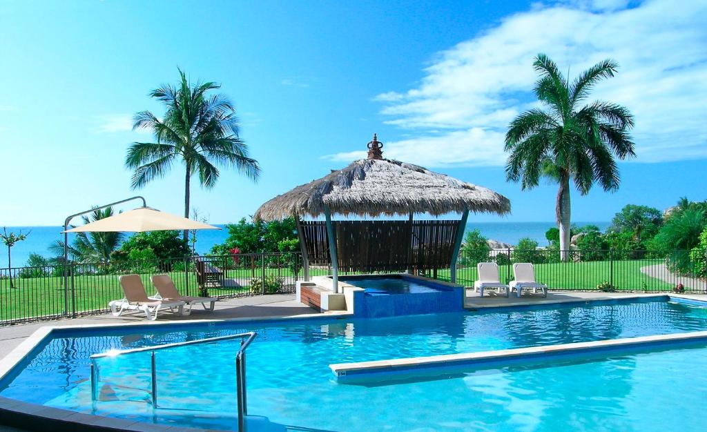 a swimming pool with a gazebo and palm trees at Coral Cove Apartments in Bowen