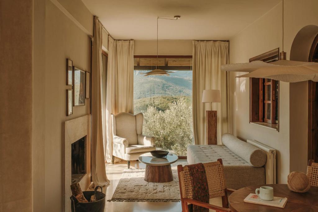 ein Wohnzimmer mit Sofa, Tisch und Fenster in der Unterkunft Endless Green, Hidden Gem in the Mountains in Artemisía
