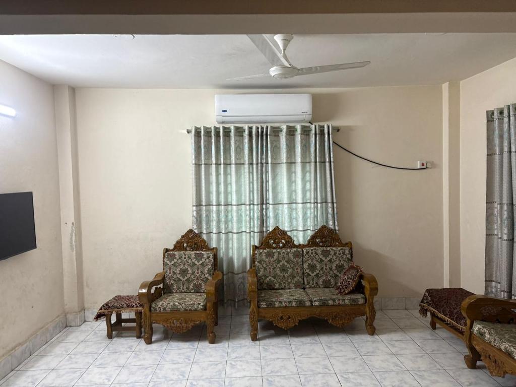 a living room with two chairs and a window at Royal Palace in Dhaka