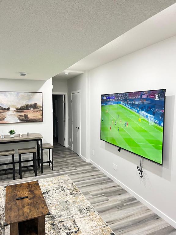 a living room with a flat screen tv on a wall at Calgary Serene Suite - 19mins from airport, 1hr to Banff, 85" Cinema, Fibre WiFi, Full Kitchen in Calgary