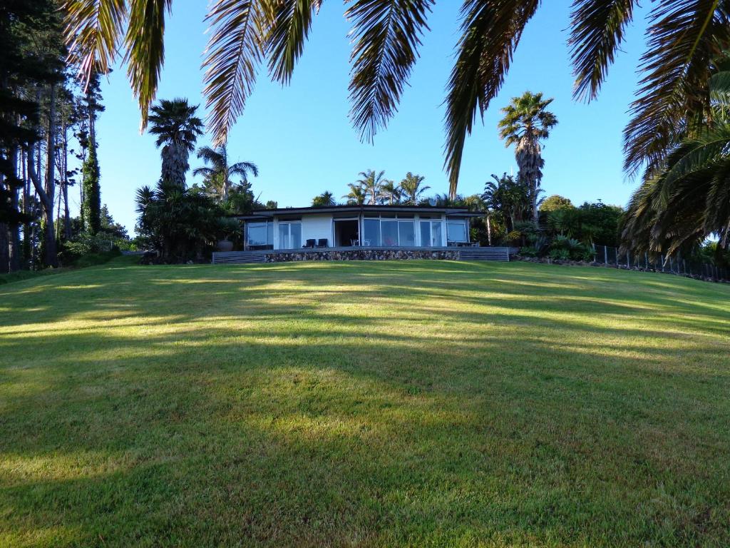 a house in the middle of a large yard with palm trees at Nikau Apartments Waiheke Island in Onetangi