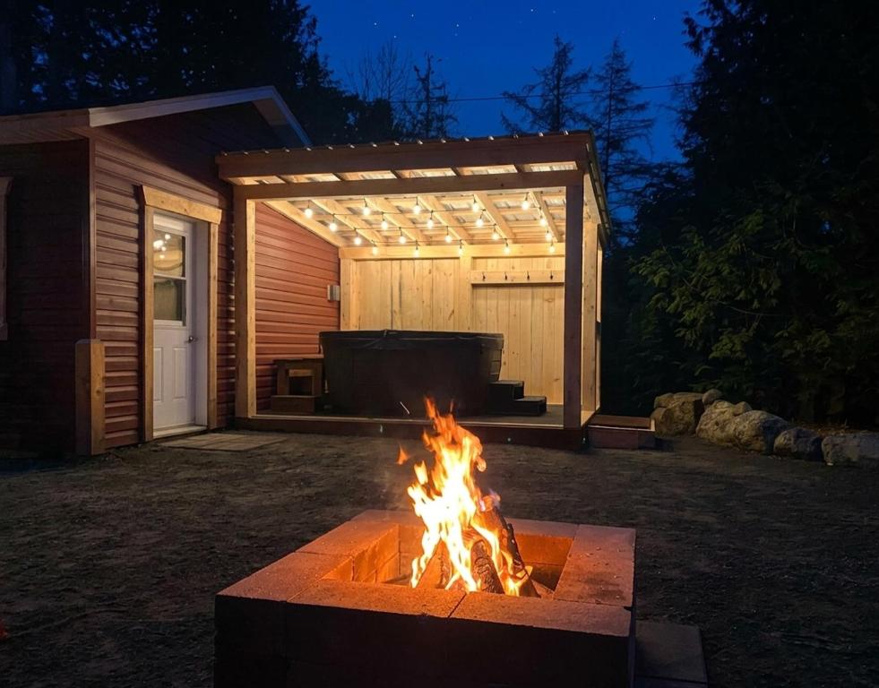 a fire pit in front of a garage at night at Chalet Relaxant sur Lac Forêt in Saint Zenon