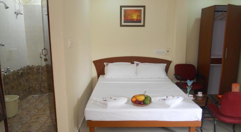 a bedroom with a bed with a bowl of fruit on it at Vijaya Guest House in Tiruvannāmalai
