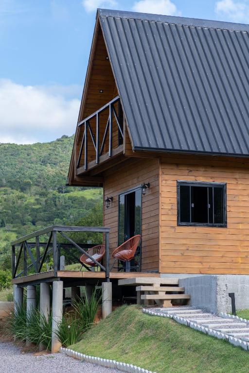 a wooden cabin with two chairs on a deck at Chalé em laguna in Pescaria Brava