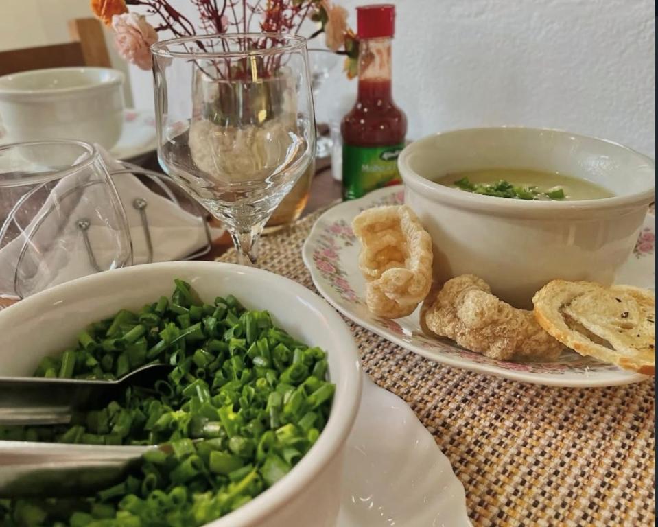 a table with a bowl of greens and a bowl of soup at Pouso das Flores - Próximo a Maria Fumaça in Tiradentes